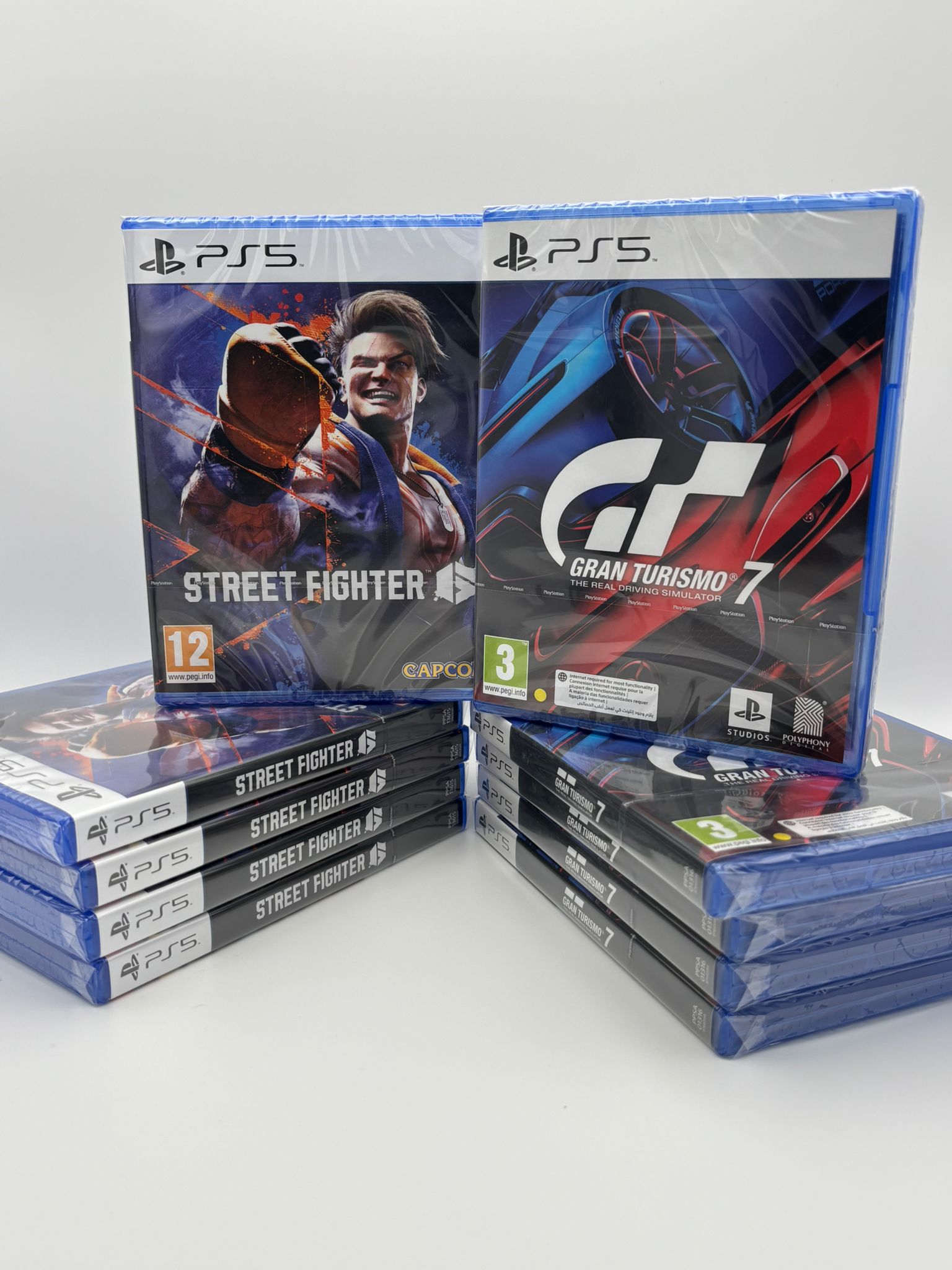 Stacks of PlayStation 5 games including 'Street Fighter' and 'Gran Turismo 7' on a white background