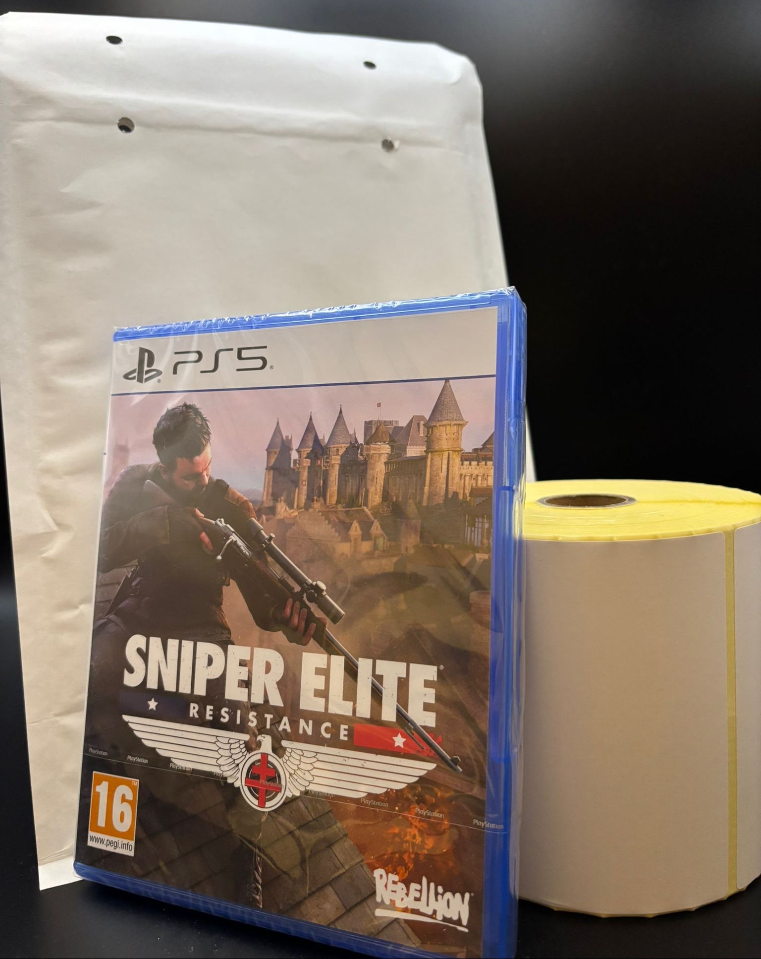 PS5 game disc of 'Sniper Elite Resistance' with a white bag and roll of paper towels.